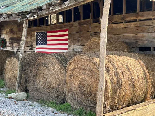 Hay bails in a barn with an American flag